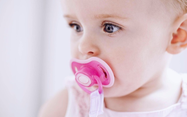 Baby with pacifier Baby with orange pacifier in his mouth with white background