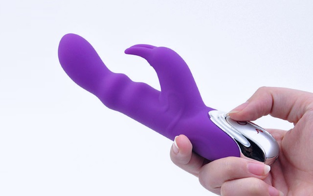 Rabbit vibrator made out of silicone material Purple silicone rabbit vibrator being held by someone with white background